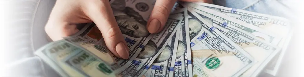 A hand holding a fan of cash